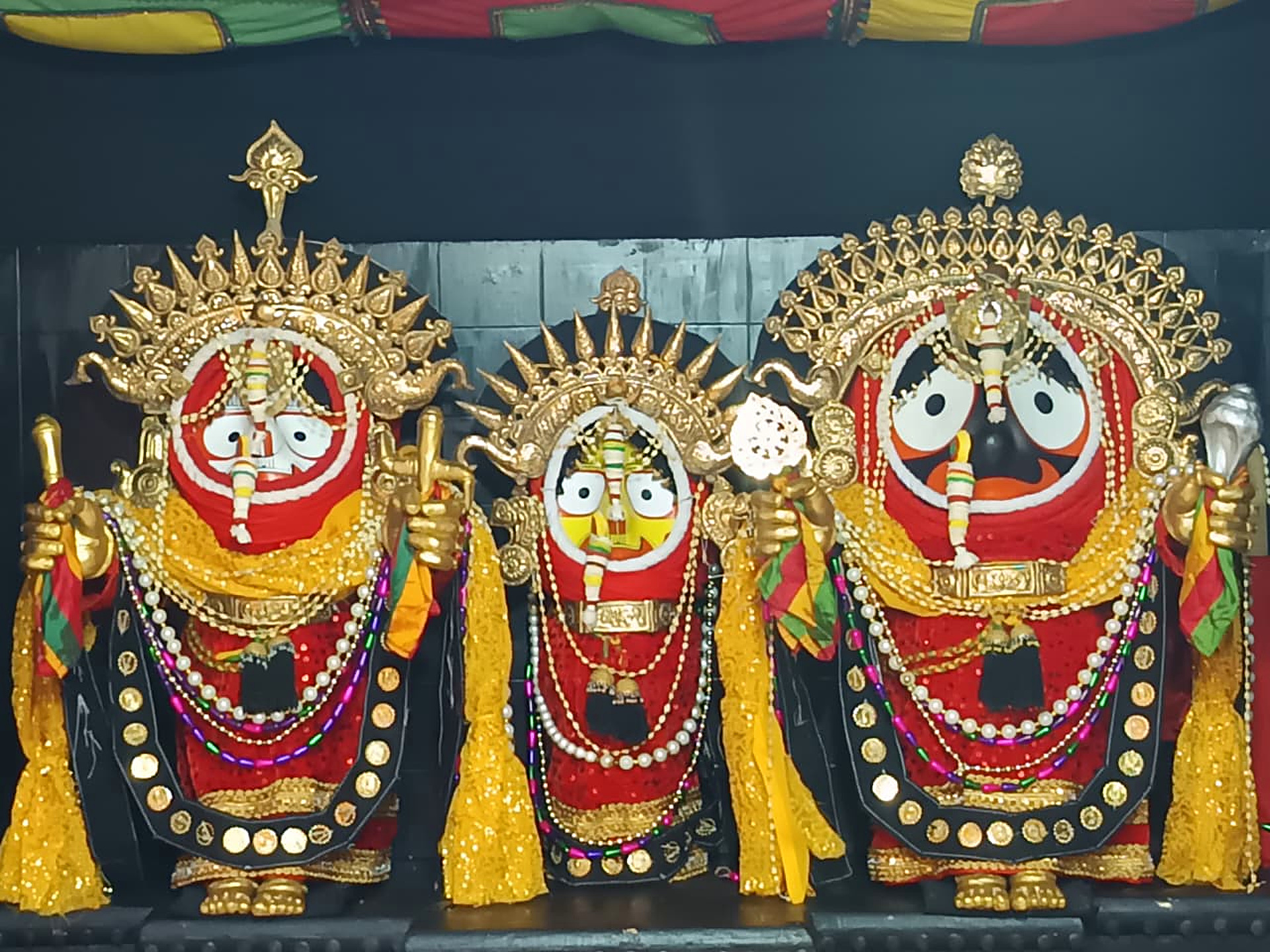 Lord Balabhadra, Devi Subhadra and Lord Jagannath adorned with gold crowns and garlands on the ratna singhasana